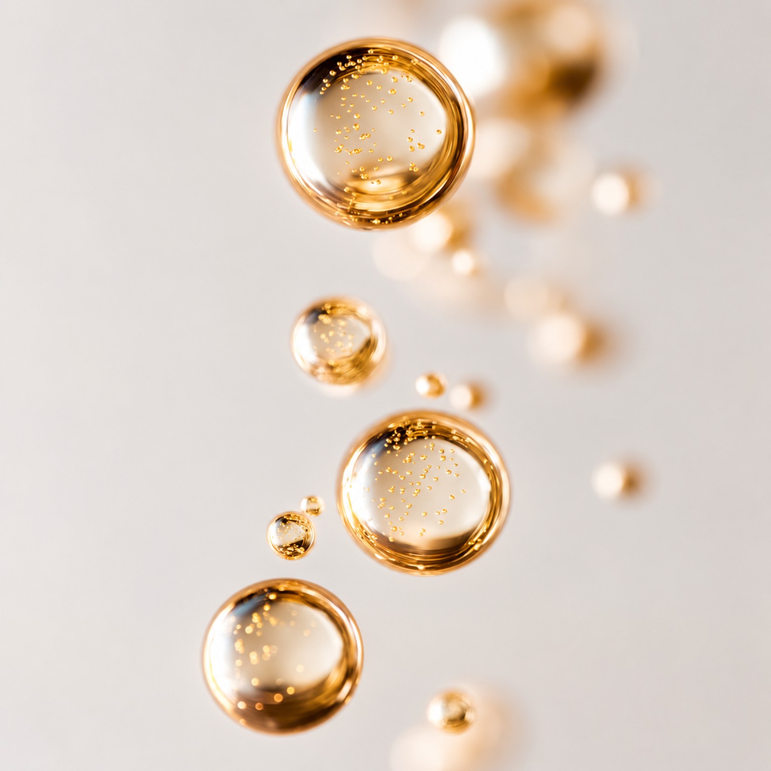 Golden luminous droplets suspended on a soft ivory background